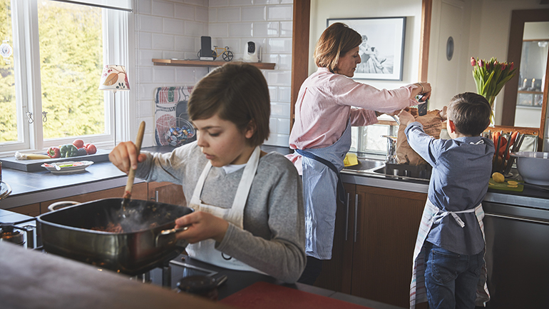 Två barn och en vuxen arbetar i köket.