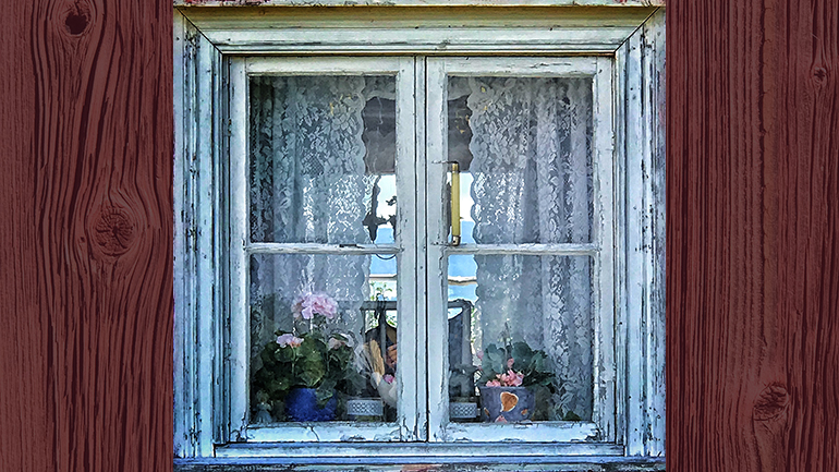 Vackert äldre fönster med spetsgardiner.