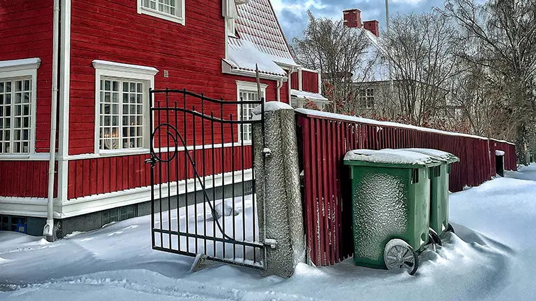 Två sopkärl utanför ett hus.