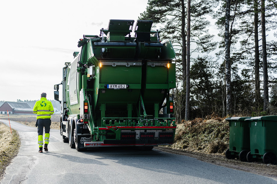 Sopbil och chaufför på landsväg.